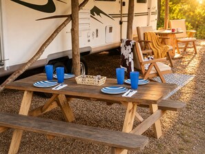 An RV with a picnic table set up in a gravel area.