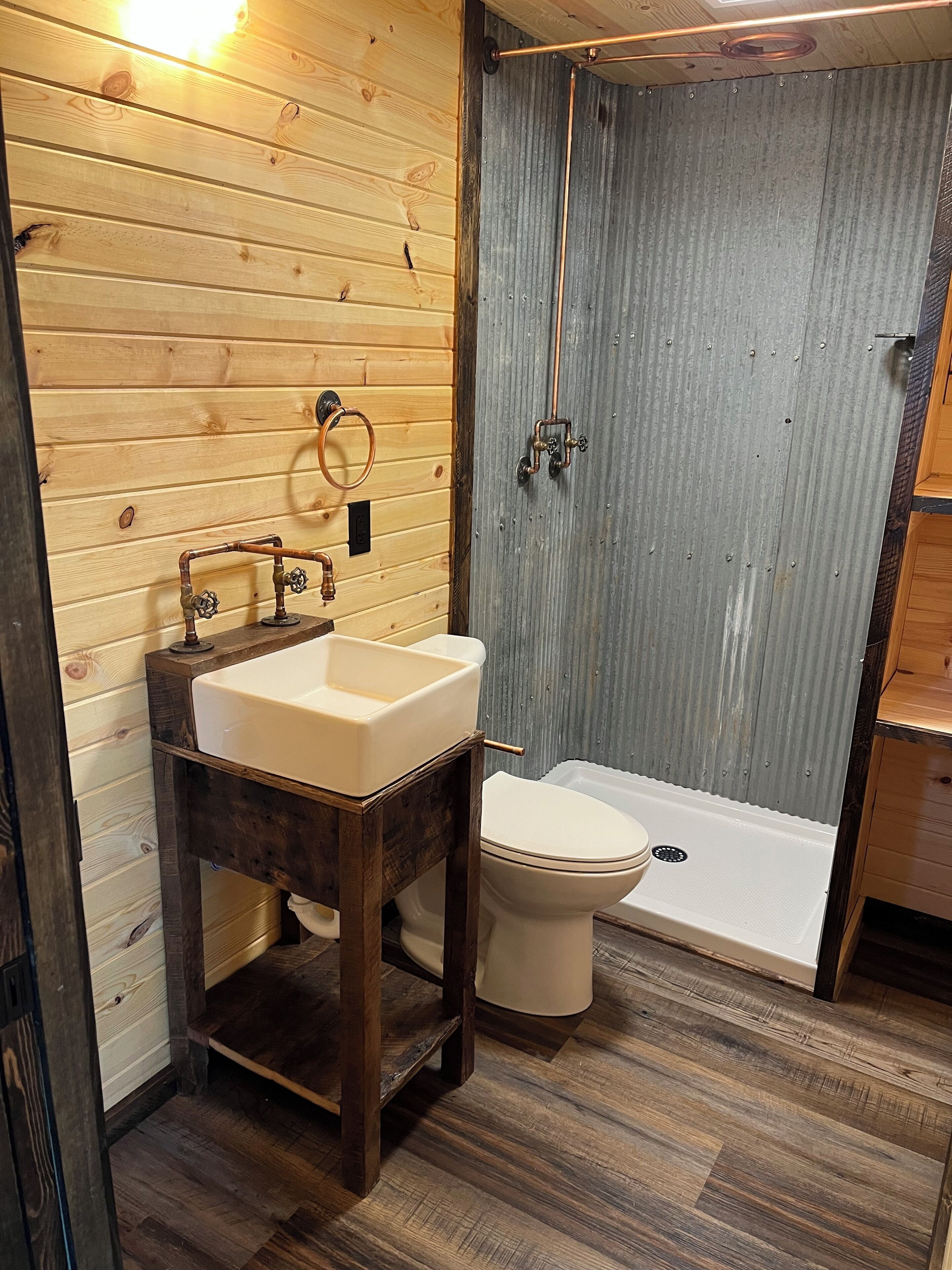 A bathroom with a wooden vanity, a sink, a toilet, and a shower area.