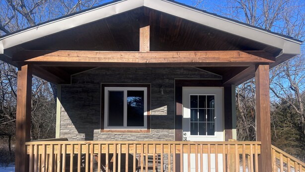 A wooden cabin with a stone exterior, a wooden deck, and a covered porch. - Quiet Cabin in the woods.  (Williamsburg)