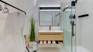 Un baño moderno con cabina de ducha de vidrio, tocador de madera y un espejo grande.