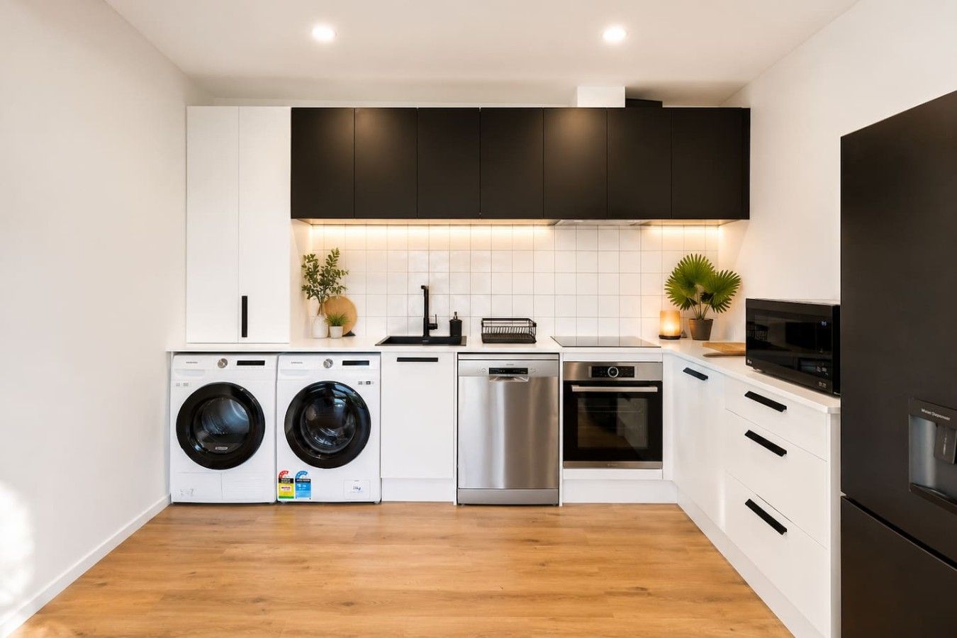 A modern kitchen with a dishwasher, oven, microwave, and washing machine.