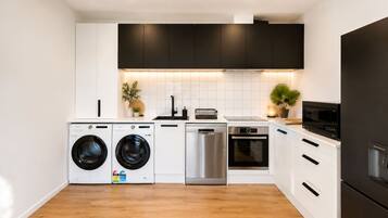A modern kitchen with a dishwasher, oven, microwave, and washing machine.