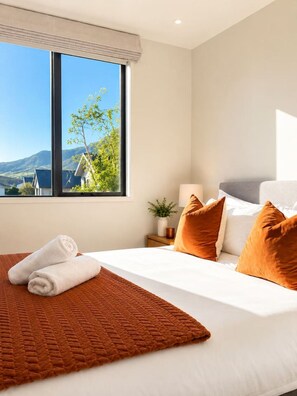 Ein Hotelzimmer mit einem großen Fenster, einem Bett mit weißer Bettwäsche und einer braunen Steude.