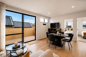 Ein modernes Hotelzimmer mit Balkon, Essbereich und Fernseher.