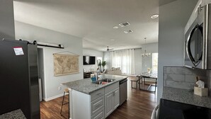 Une cuisine moderne dot ée d’un îlot central, d’appareils électroménagers en acier inoxydable et d’un coin repas offrant une vue sur le salon.
