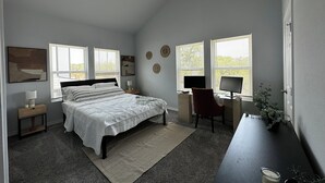 Une chambre à coucher comprenant un lit, un bureau, une chaise et un ventilateur de plafond.