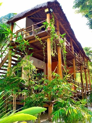 Una estructura de madera con techo de paja, rodeada de exuberante vegetación.