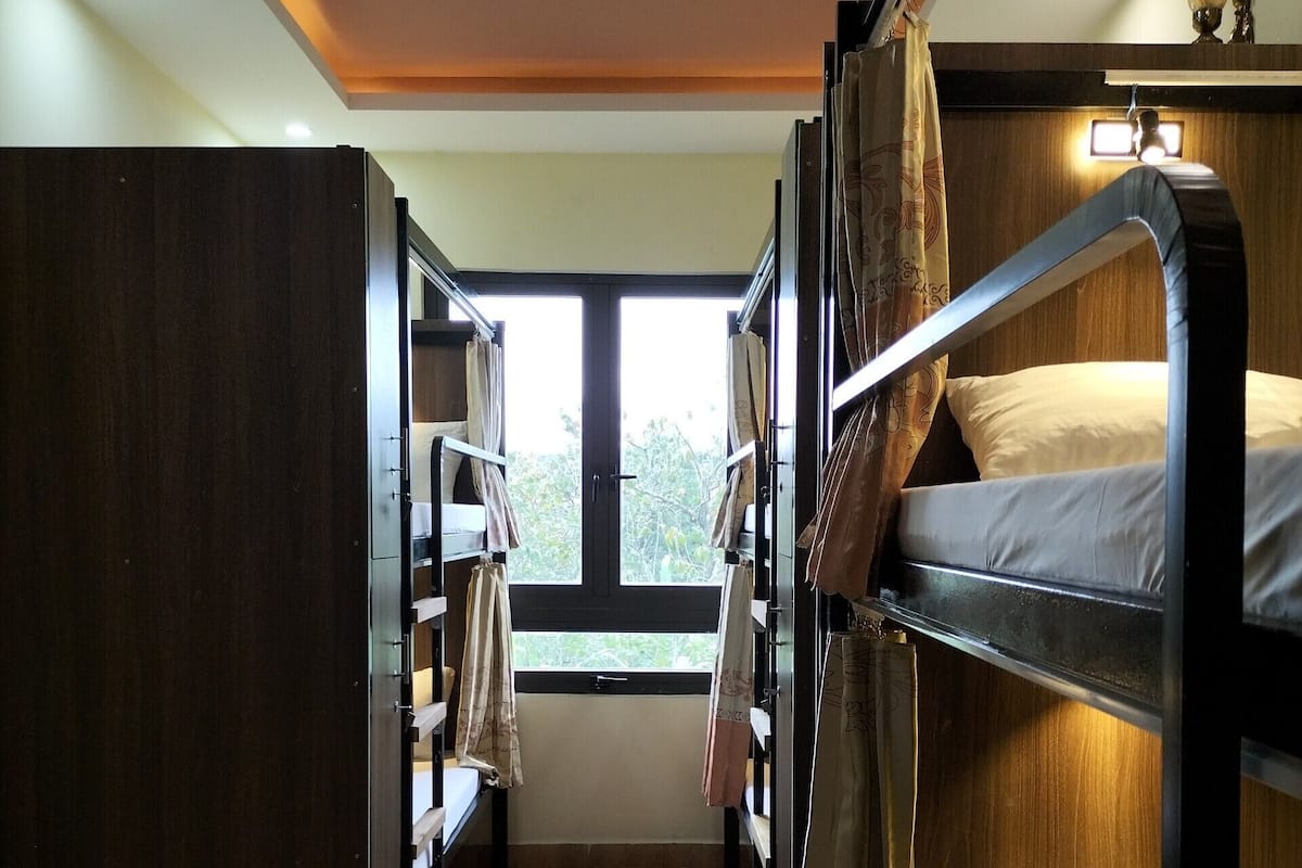 Un dormitorio con literas, un armario y una ventana que proporciona luz natural.
