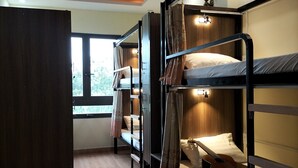 A bunk room with wooden bunk beds, a small table with a guitar and sheet music, and a window with curtains. - Ngoc Tran Hostel (Cam Ly - Da Lat)