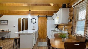 Une cuisine compacte agrémentée de touches de bois, un coin repas avec une table et des chaises, et une horloge au mur.