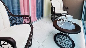 En balkon med to stole, et lille bord og en cykel.