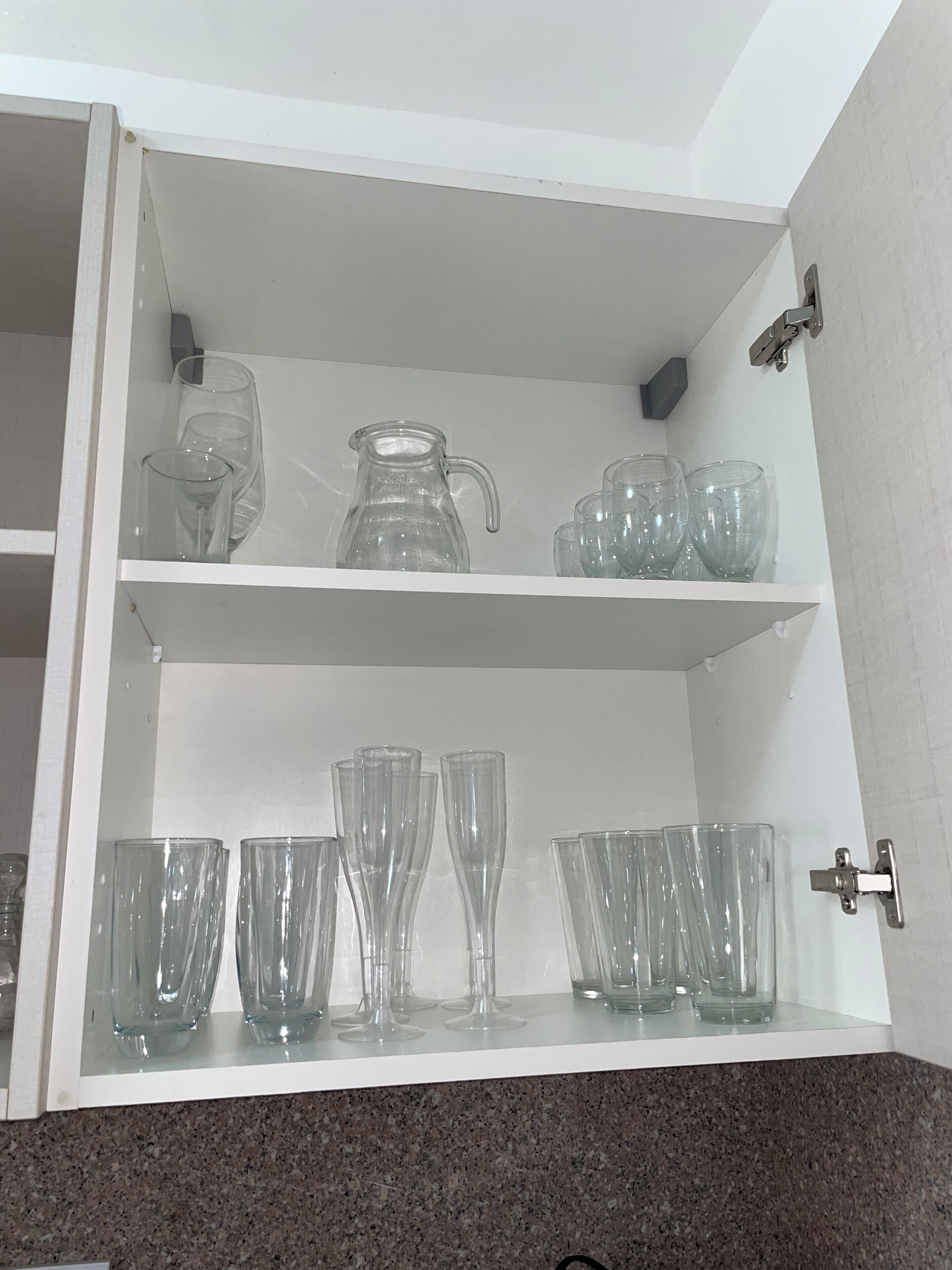 Un meuble de cuisine contenant de la verrerie et une carafe.