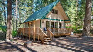A lodge with a wooden deck, a covered porch, and a staircase leading to the entrance. - Peaceful Leavenworth Cabin with Deck & Fire Pit! (Leavenworth)