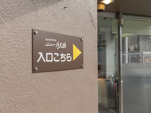 Un panneau avec du texte en japonais et une flèche pointant vers la droite, indiquant la direction de l’entrée.