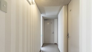 Un pasillo estrecho y bien iluminado con paredes a rayas y piso liso, que conduce a una puerta con el número 305.