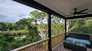 A covered porch with a view of a pond and trees. - New modern home, 3 minute walk to the beach, on bike trail, full RV hookup (Panacea)