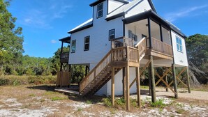 A two-story house with a balcony and a wooden staircase. - New modern home, 3 minute walk to the beach, on bike trail, full RV hookup (Panacea)