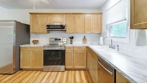 Une cuisine moderne avec des meubles en bois, des appareils électroménagers en acier inoxydable et une fenêtre.