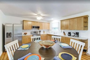Una cocina moderna con armarios de madera, una isla central y una mesa de comedor para cuatro.