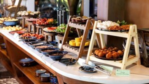 A buffet with various dishes including corn on the cob, fried items, and a sign indicating Vietnamese pork ham. - Tam Coc Retreat Ninh Bình (Nam Hoa Lu)