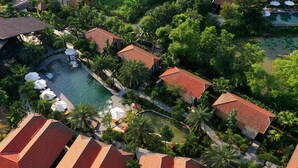 An aerial view of a resort with multiple buildings, a swimming pool, and lush greenery. - Tam Coc Retreat Ninh Bình (Nam Hoa Lu)