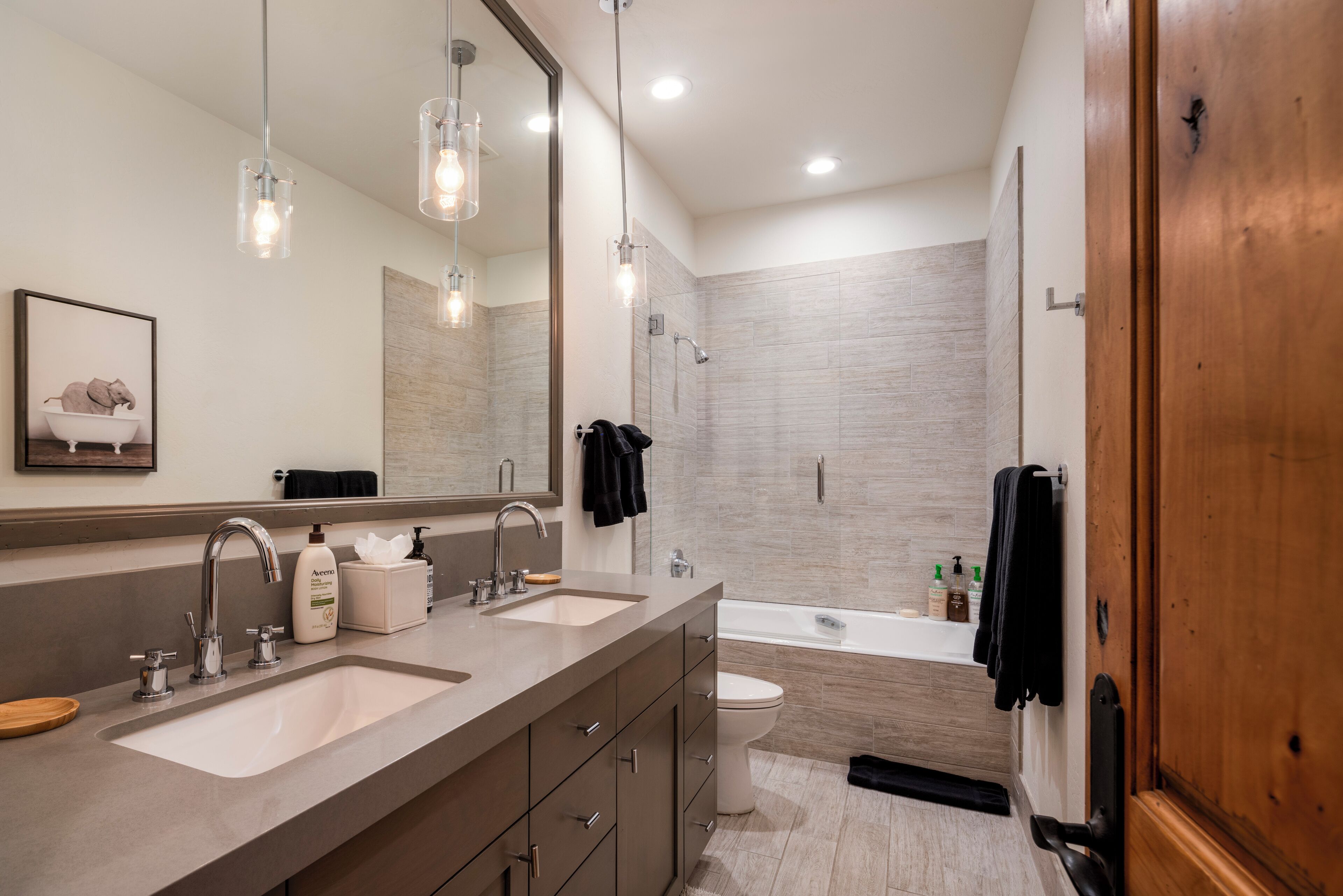 Un baño moderno con dos lavamanos, un espejo grande y una bañera.