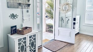 A modern interior with a wooden cabinet, a basket, and a door leading outside. - Stunning and Clean Hidden Gem w/ 2 Pools Beach Golf & Shops in Barefoot (North Myrtle Beach)