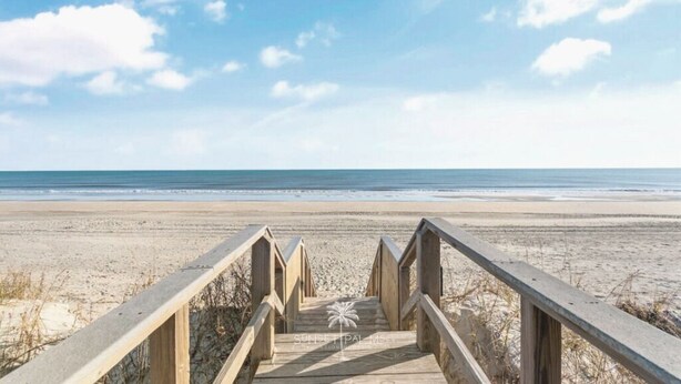 A wooden boardwalk leading to a beach with a palm tree symbol in the center. - Stunning and Clean Hidden Gem w/ 2 Pools Beach Golf & Shops in Barefoot (North Myrtle Beach)