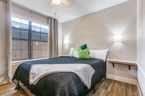 A bedroom with a bed, a window with curtains, a ceiling fan, and wall-mounted lights. - Estrella Tejana House close to Downtown (Pasadena)