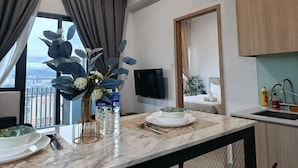 A modern hotel room with a dining area, a large window with curtains, a flat-screen TV, and a view of the cityscape. - The Colony Skyline Suites KLCC (Kuala Lumpur)