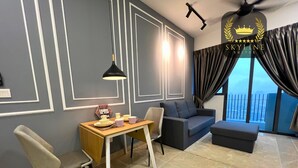 A modern living room with a sofa, a dining table with chairs, a ceiling fan, and a view of the city through large windows. - The Colony Skyline Suites KLCC (Kuala Lumpur)