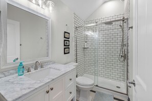 A bathroom with a white marble sink, a toilet, and a glass-enclosed shower. - Waterfront Condo, Private Beach, Outdoor Pool & Hot Tub & Walkable to Downtown (Elkhart Lake)