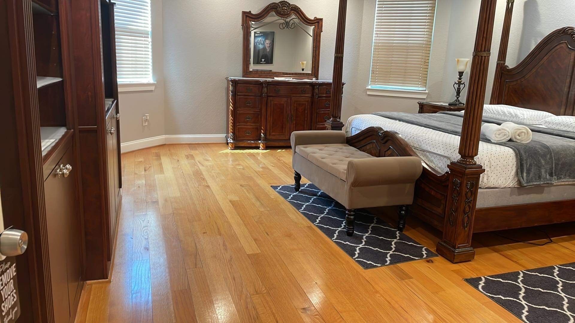 A bedroom with a four-poster bed, a dresser, and a mirror.