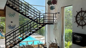 Ein geräumiger Wohnbereich mit einer modernen Treppe, großen Fenstern und Blick auf einen Swimmingpool.