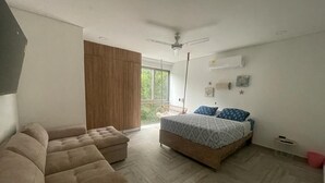Ein Schlafzimmer mit Bett, einer Couch, einem Deckenventilator und einem Fenster.
