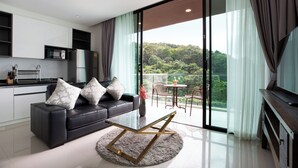 A modern living room with a sofa, coffee table, and a view of a balcony with outdoor furniture. - Condo Viva Patong A401 Freedom Beach (Patong)