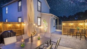 Una casa con un porche cubierto, mobiliario exterior y luces colgantes.