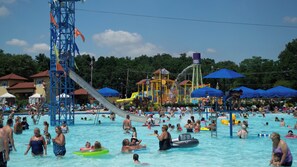Um parque aquático movimentado, com vários tobogãs, piscinas e guarda-sóis.