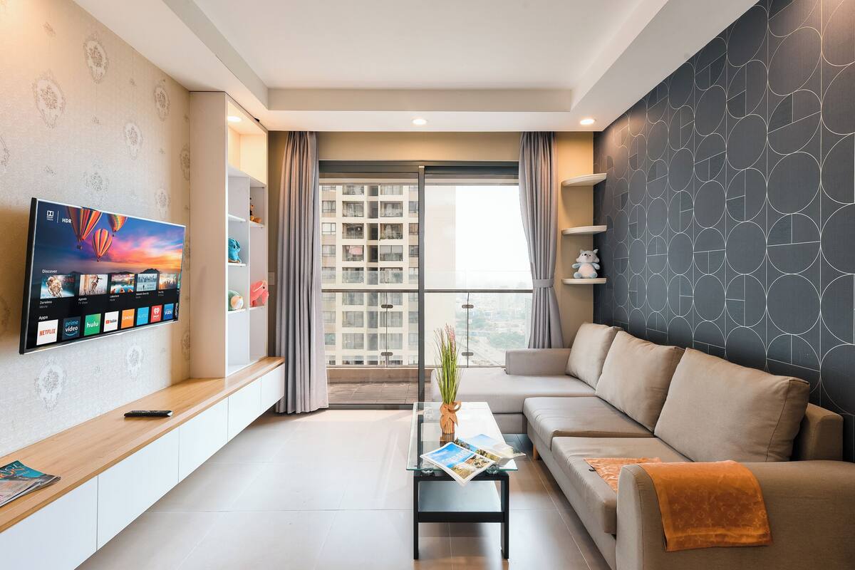 A modern living room with a sofa, a coffee table, and a flat-screen TV mounted on the wall.