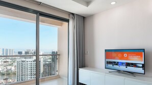 A modern living room with a large window, a flat-screen TV, and a white entertainment unit. - Gold View Saigon Riverside (Ho Chi Minh City)
