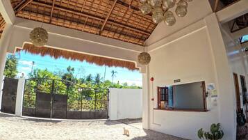A covered outdoor area with a thatched roof, hanging lanterns, and a reception desk.