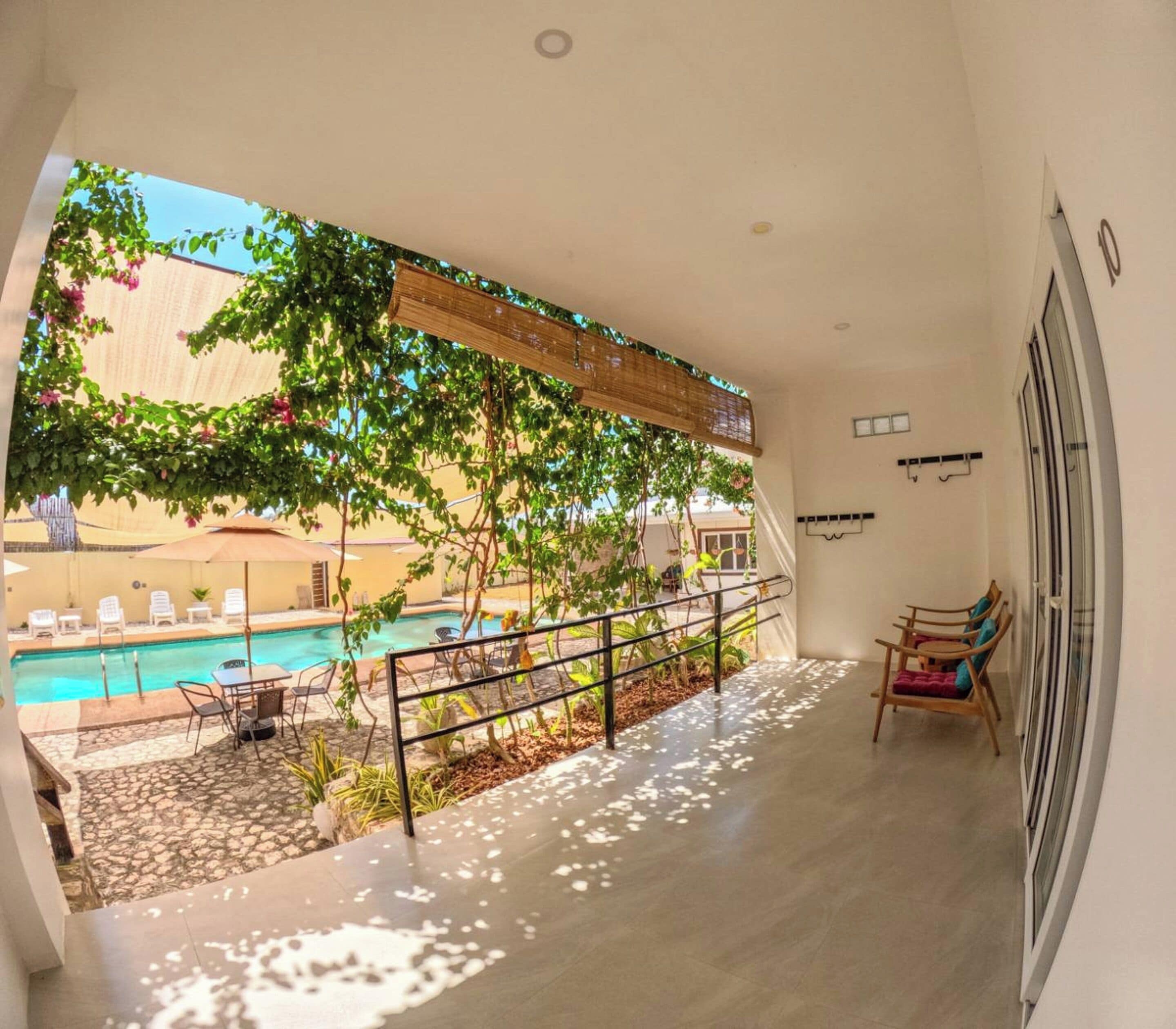 Ein Balkon mit Blick auf einen Swimmingpool, Gartenmöbel und Geländer.
