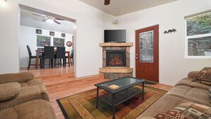 Un salón con chimenea, televisor y comedor con sillas y una mesa.