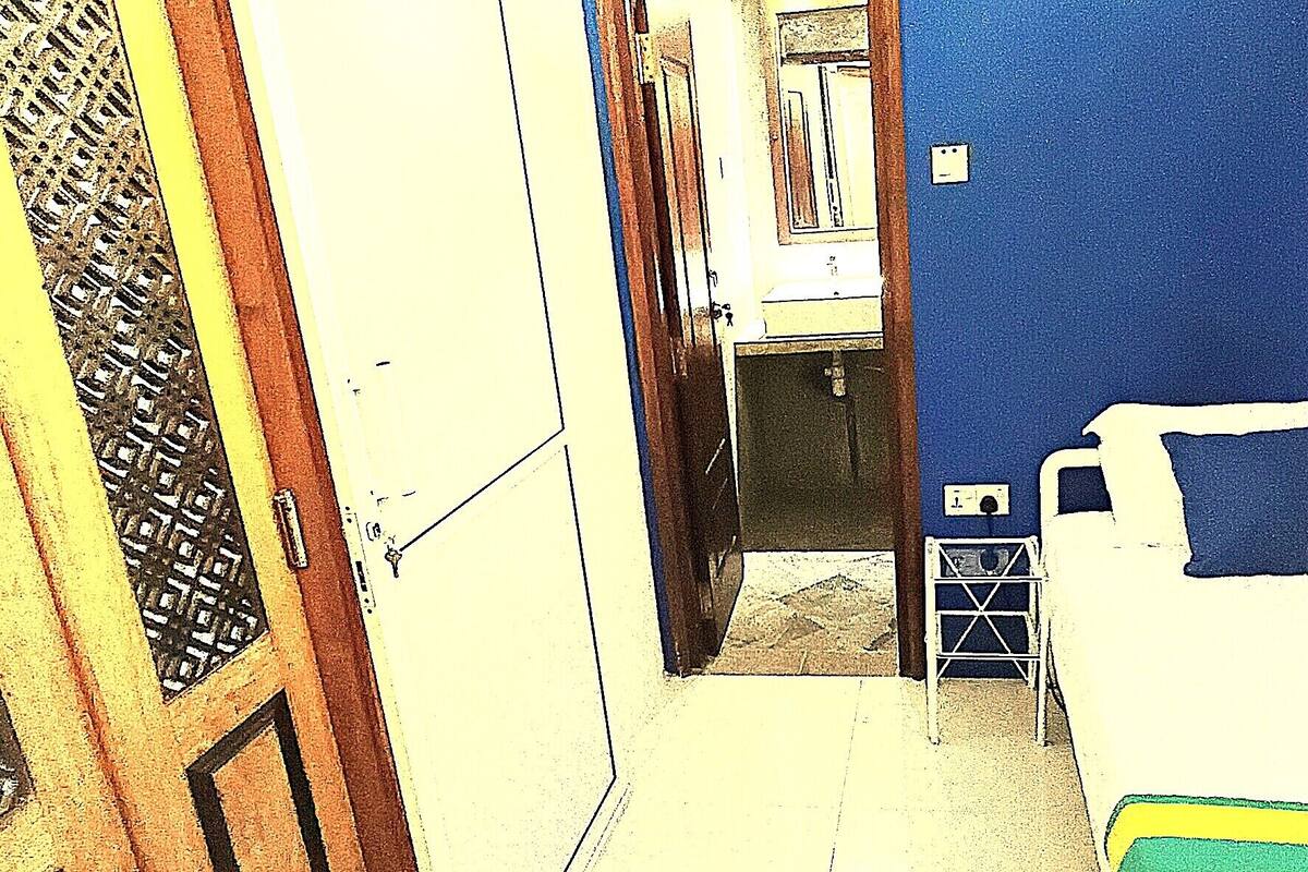 A room with a bed, a small table, a chair, a window with curtains, and a door.