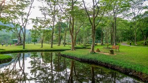 Ein friedlicher Park mit Teich, Bänken und einem Pavillon.
