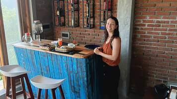 A bar area with a blue-painted counter, stools, and a brick wall backdrop.
