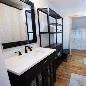 Un baño moderno con un lavamanos blanco, accesorios negros y un espejo grande.