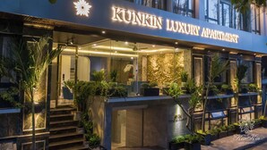 Ein luxuriöses Apartmenthaus namens Kunkin Luxury Apartment mit modernem Design, ausgestattet mit einem gut beleuchteten Eingangsbereich, einer Treppe und verschiedenen Topfpflanzen.