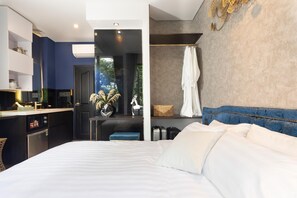 Ein modernes Hotelzimmer mit einem großen Bett, einem separaten Badezimmer, einer Küchenzeile und Blick ins Freie.