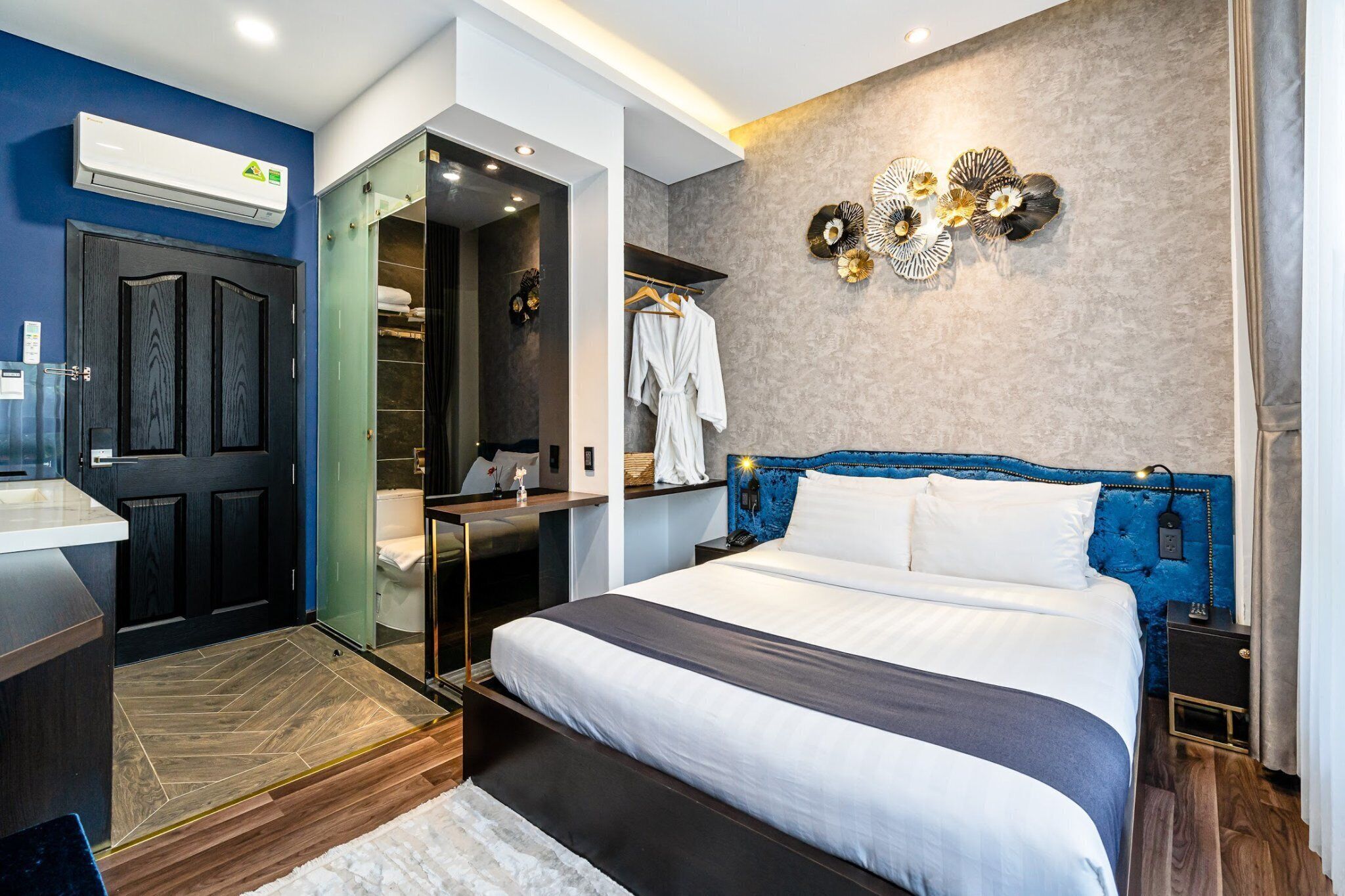 A modern hotel room with a large bed, a walk-in closet, and a bathroom with a glass door.